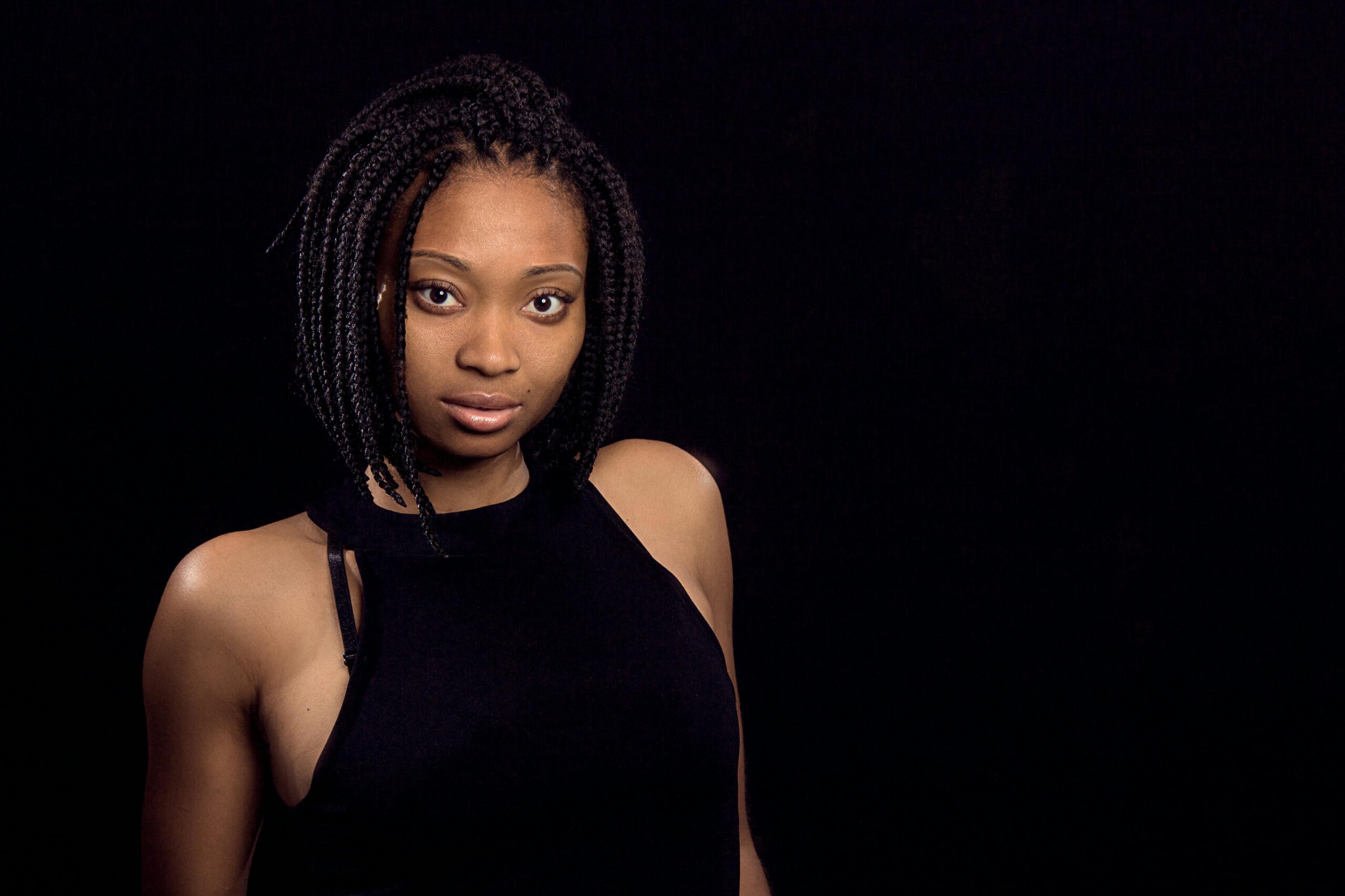 A stunning portrait of a black woman with braided hair, exuding confidence against a dark background.